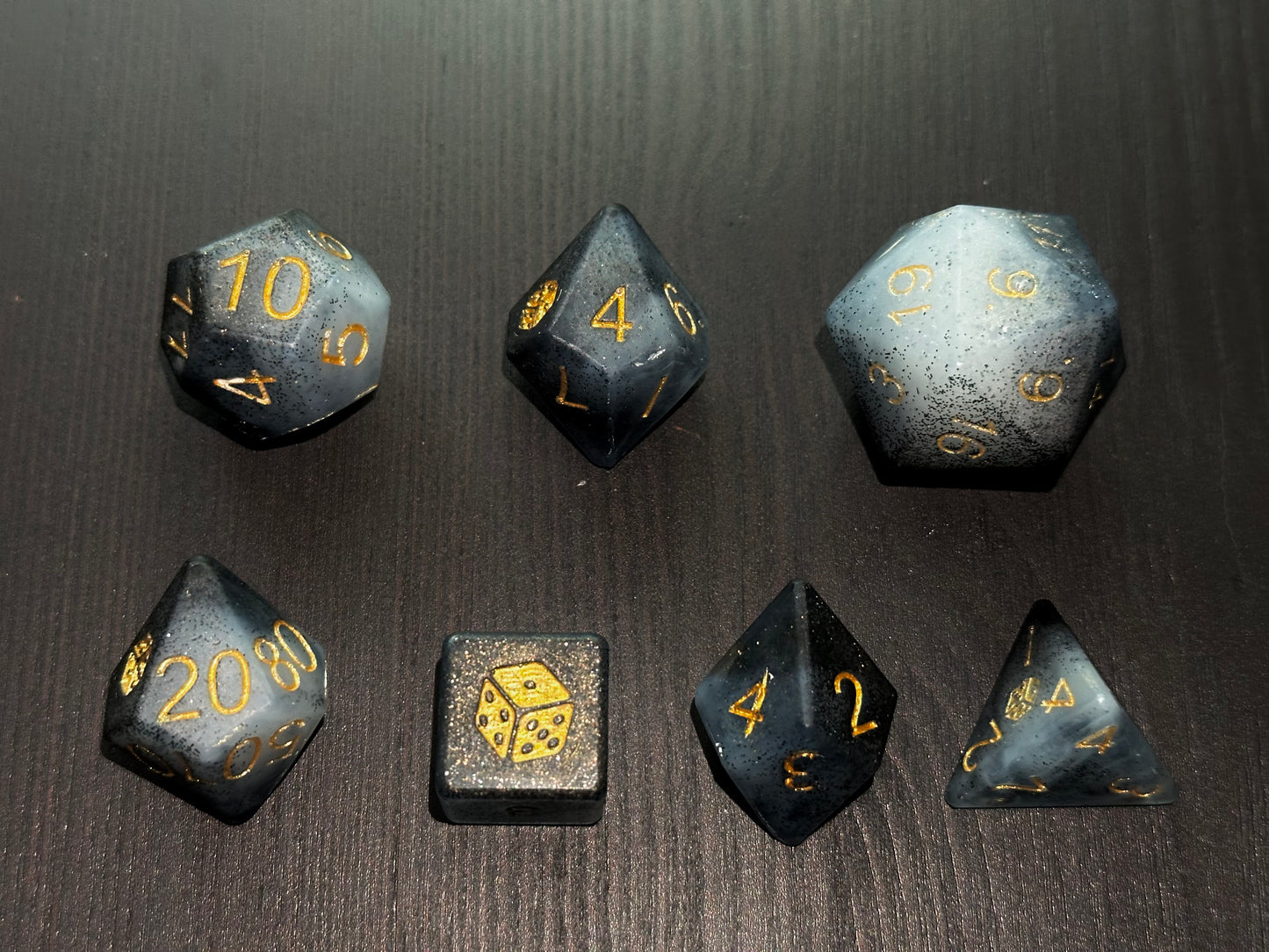 Czarno-biały grafitowy zestaw kostek RPG premium na stole – ręcznie robione kości do gier fabularnych
