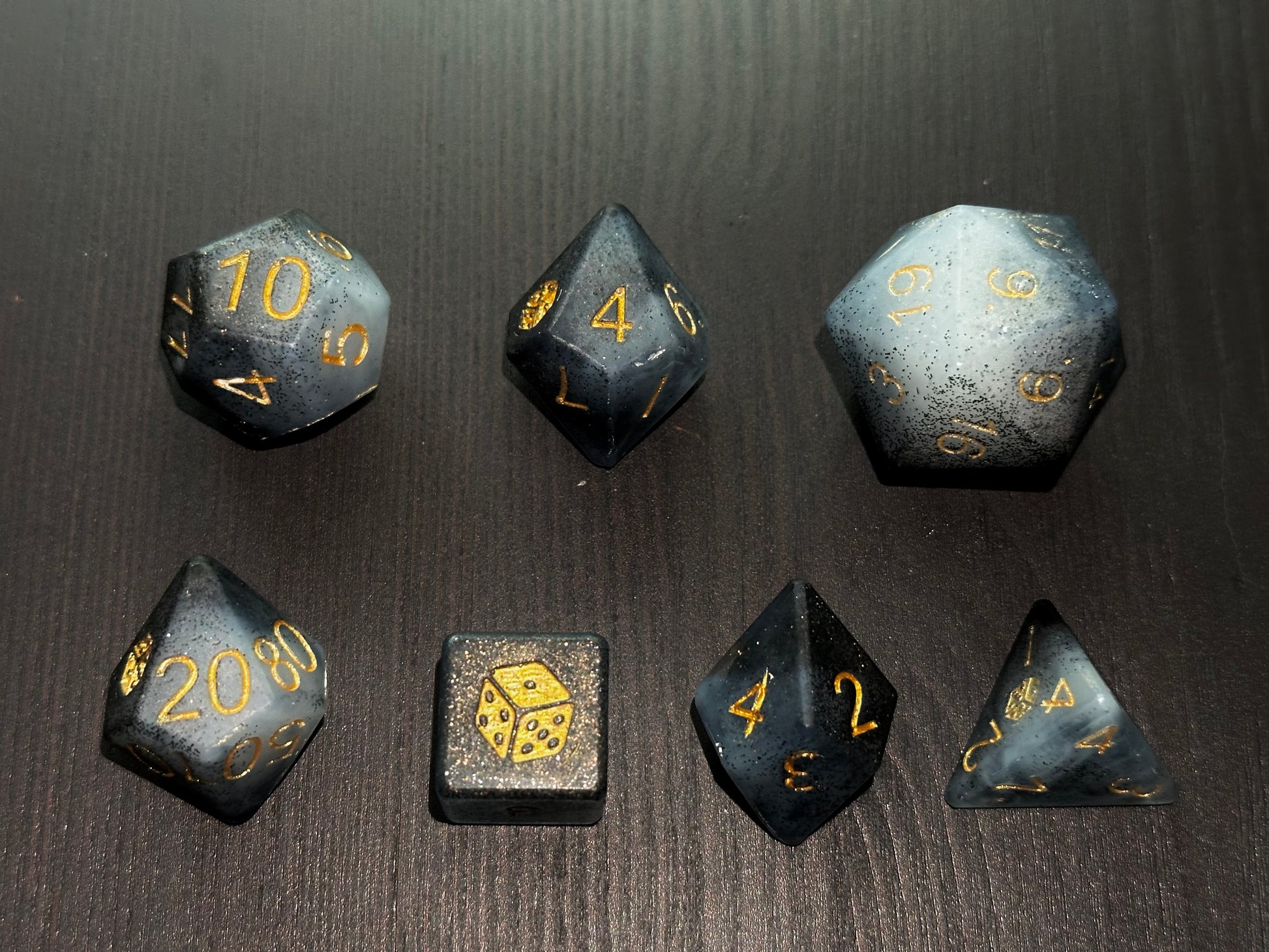 Czarno-biały grafitowy zestaw kostek RPG premium na stole – ręcznie robione kości do gier fabularnych