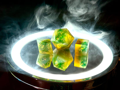 Pomarańczowo-zielone żywiczne kostki RPG na podświetlonym tle z dymem, kostki do DnD.