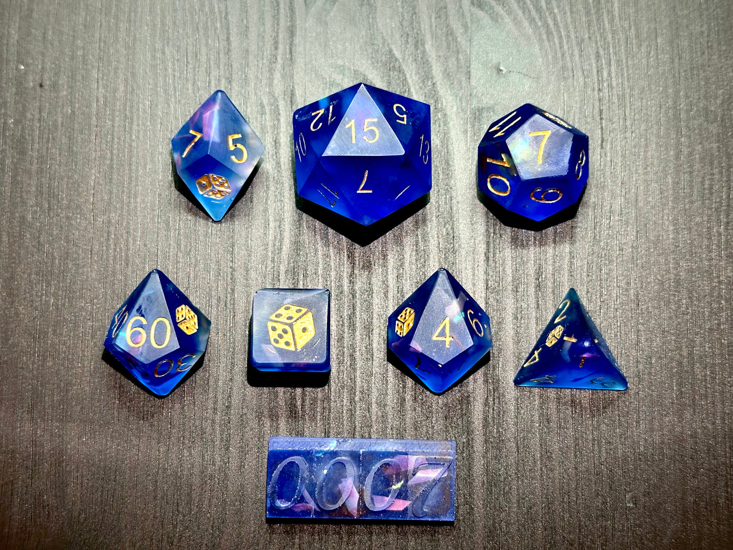 Niebieskie kostki RPG z holo drobinkami i złotymi cyframi na czarnym stole, zestaw premium.