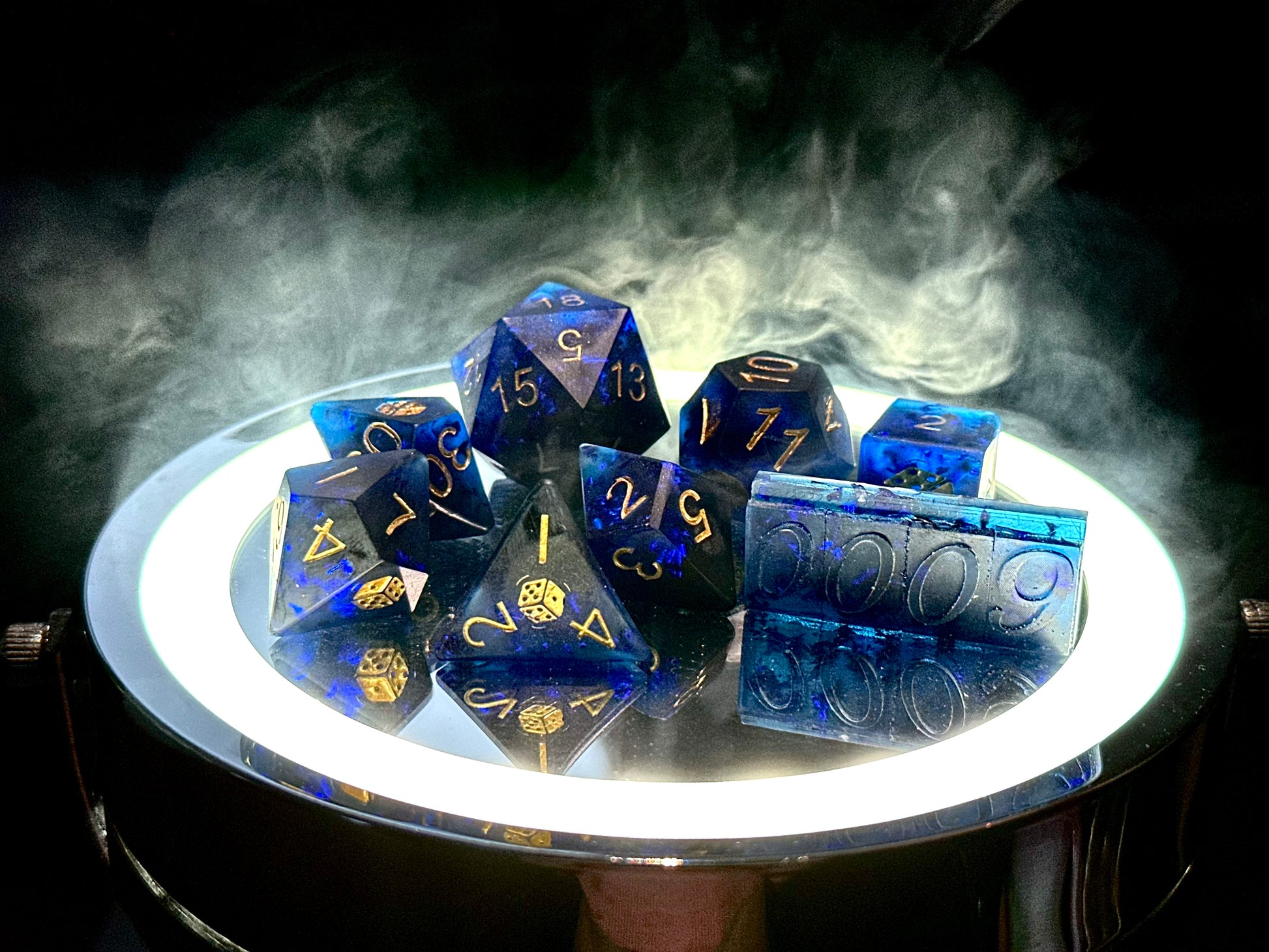 Niebiesko-czarny, ręcznie robiony zestaw kostek RPG z żywicy z numerem seryjnym, podświetlony na tle dymu.