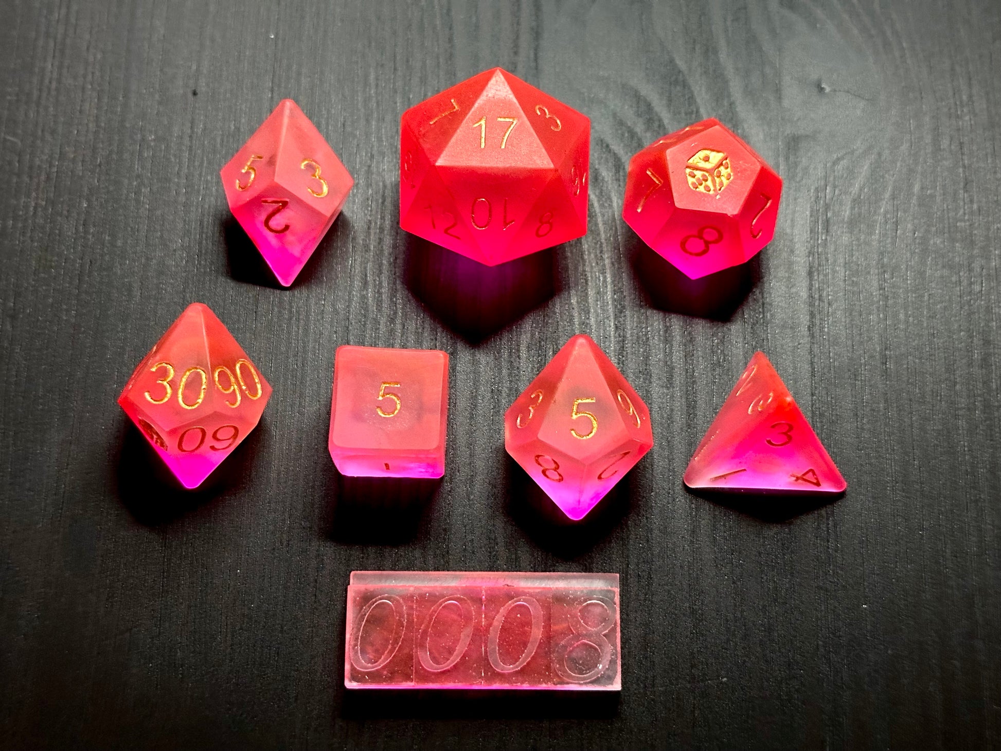 Ręcznie robione neonowe kostki RPG z żywicy na czarnym stole, idealne do DnD i gier fabularnych.