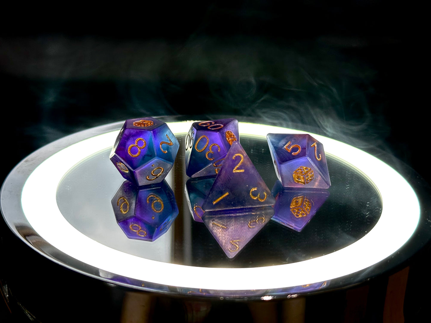Zestaw fioletowo-niebieskich kostek RPG z żywicy na lustrzanej tacy, numery w złotym kolorze